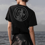 Person wearing a black t-shirt with a logo on the beach